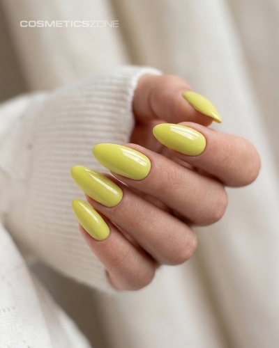 Dłonie z manicure hybrydowym w kolorze A019 Lime Sorbet – intensywny, neonowy odcień limonki na paznokciach o migdałowym kształcie.