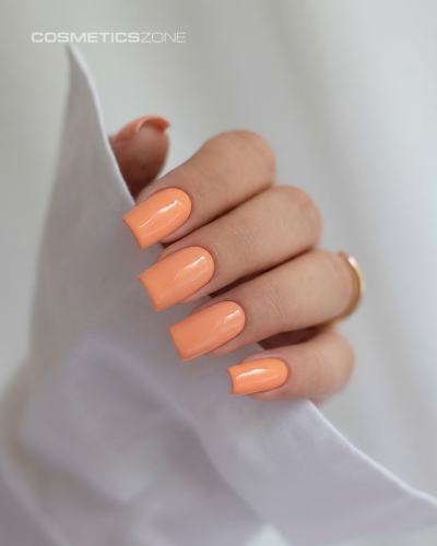 Dłonie z manicure hybrydowym w kolorze A020 – soczysty, brzoskwiniowy odcień na paznokciach o kwadratowym kształcie.
