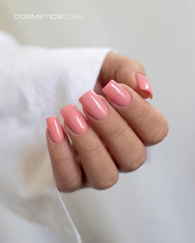 Dłonie z manicure hybrydowym w kolorze A021 – delikatny, cukierkowy róż na paznokciach o kwadratowym kształcie.