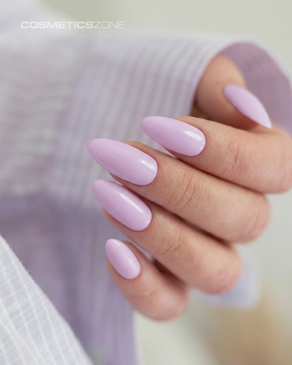 Dłonie z manicure hybrydowym w kolorze A022 – subtelna, jasna lawenda na paznokciach o migdałowym kształcie.
